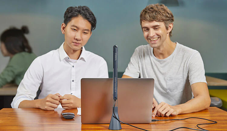 木製のテーブルでラップトップとマイクロフォンを使用して協力する二人の男性。