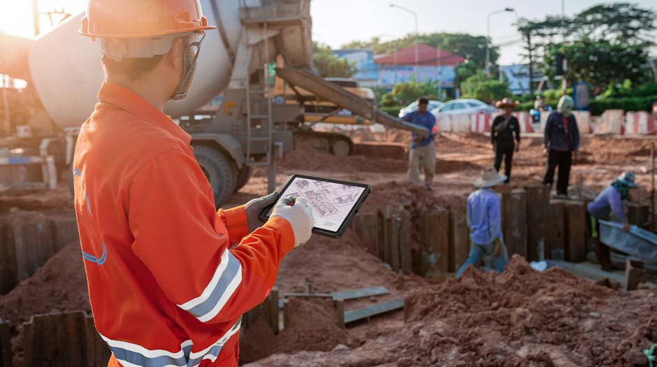 忙しい建設現場の従業員が、Lenovo ThinkTab X11タブレットを持っている様子。