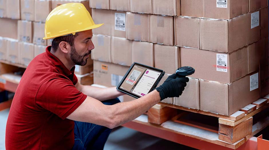 Lenovo ThinkTab X11タブレットを持って、倉庫の作業員が箱をスキャンしている様子。