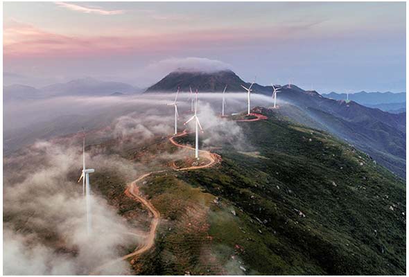 雲海と風力発電の風車が連なる山並みの風景。