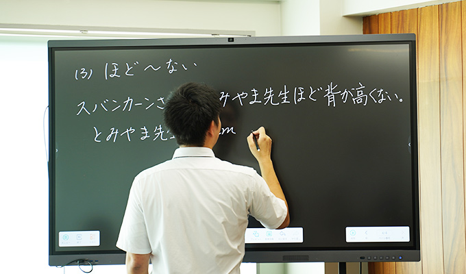 電子黒板に文字を書く先生。