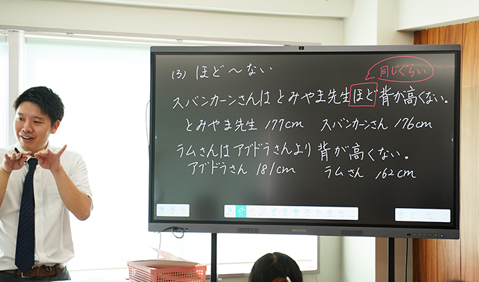 電子黒板の前で説明する先生。