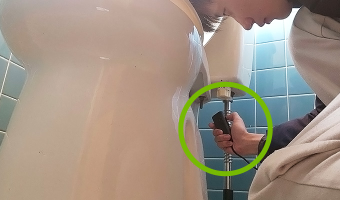 修繕箇所の便座の裏側をIPEVO P2V ULTRAカメラを使って撮影する設樂様。